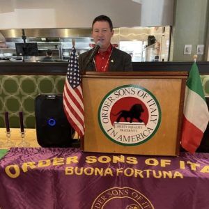 Dan Kaestle, President, Buona Fortuna Lodge #2835 OSDIA, stands at a podium and speaks at a lodge meeting.